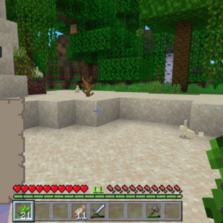 a screenshot of Minecraft, a sandy desert area with some jungle forest next to it. 3 bunnies are hanging out.