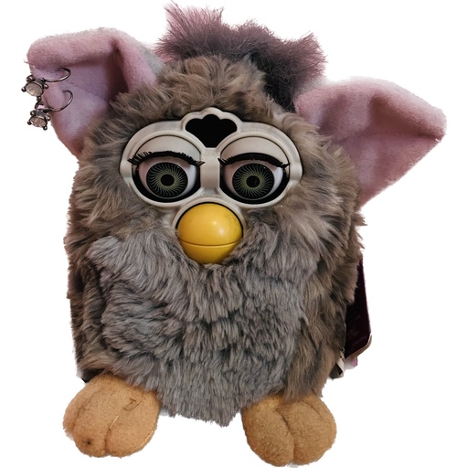 Pickle Spice, a patchy gray Furby toy with large blinking eyes and a beak wearing two diamond earrings in one ear